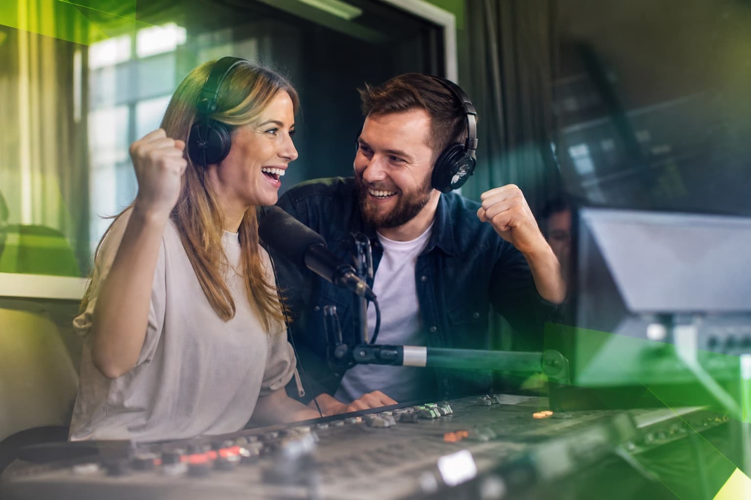 A radio presenter and producer celebrating a competition winner in the studio